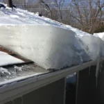 Large ice dam buildup on residential roof gutters with snow