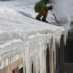 Roof gutter covered with thick ice dam formation during winter