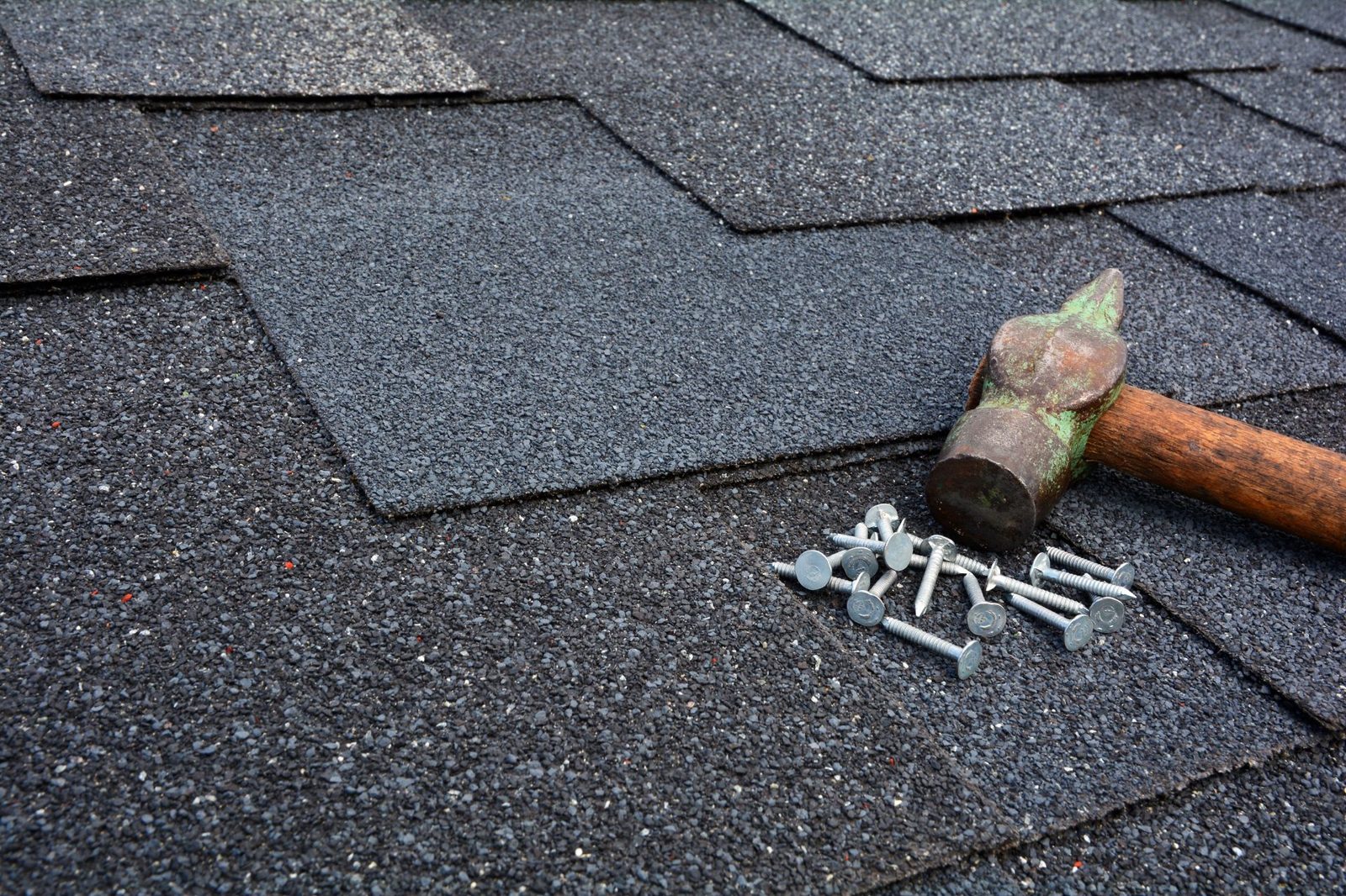 Medina OH Roofing Repair & Replacement | Roof Gutter Now 2 Roofing hammer and galvanized nails positioned on asphalt shingles for roof repair work in Medina, OH