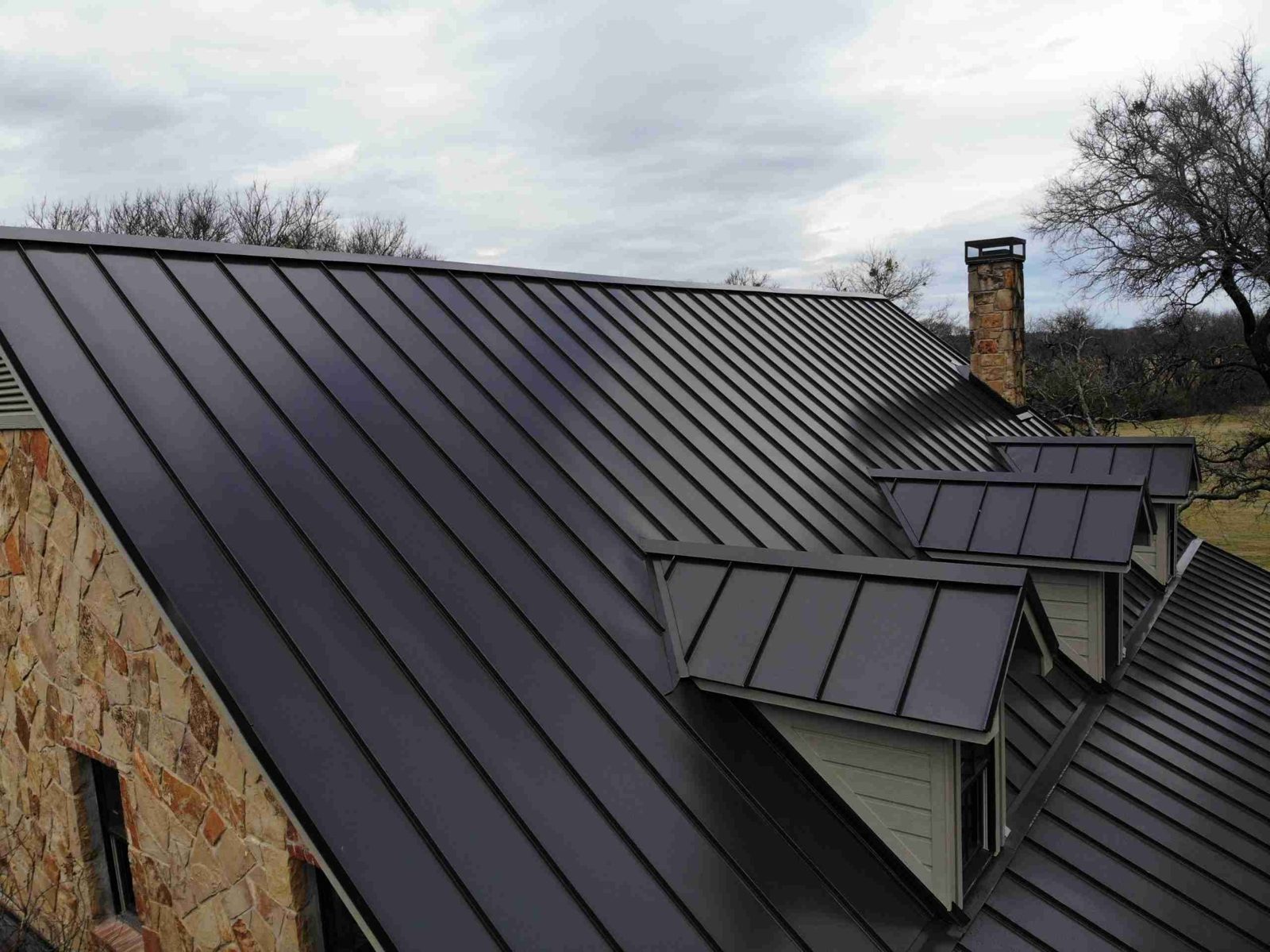 Black standing seam metal roof with chimney and dormers