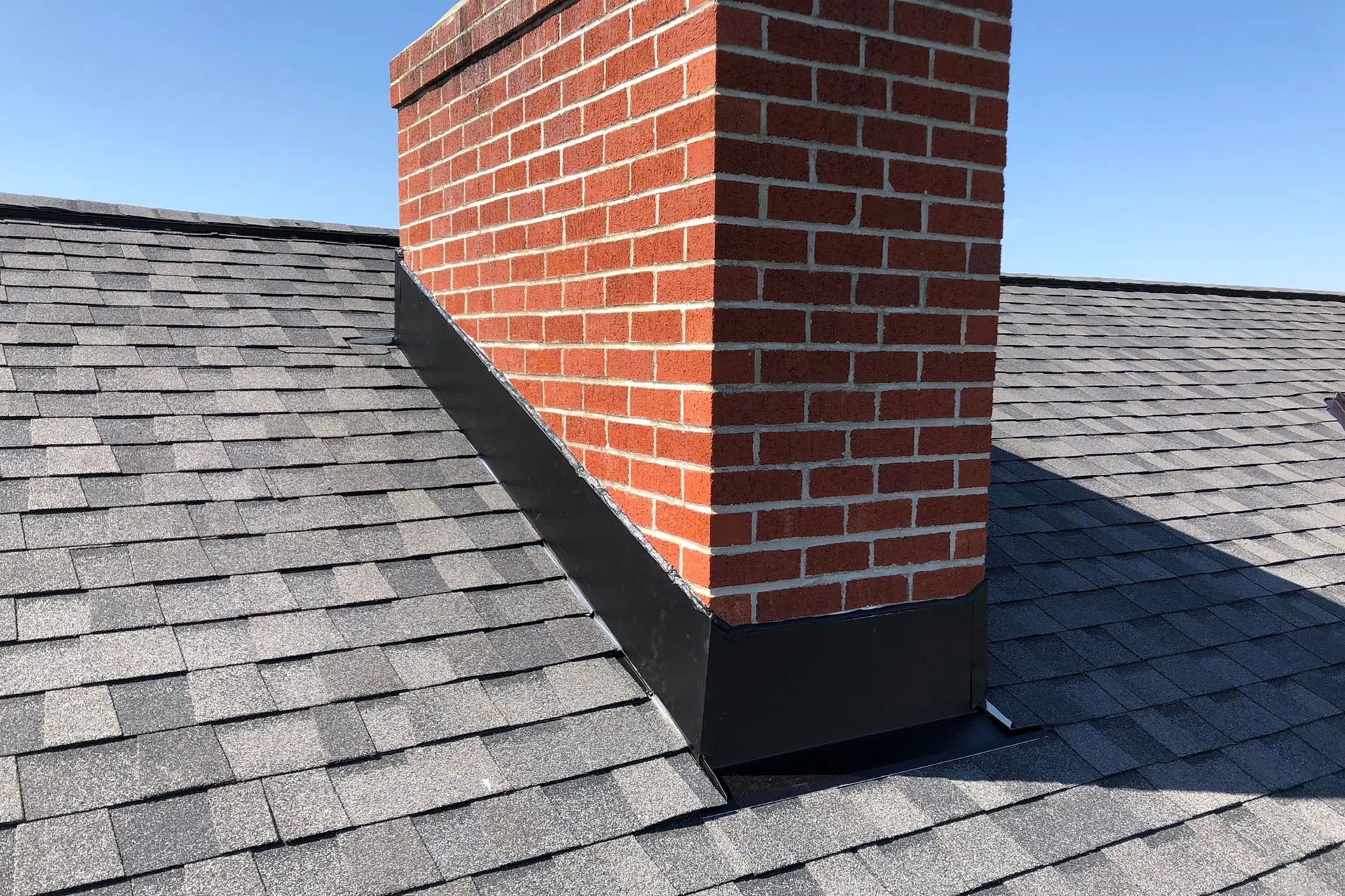 Brick chimney with complete flashing system on shingle roof