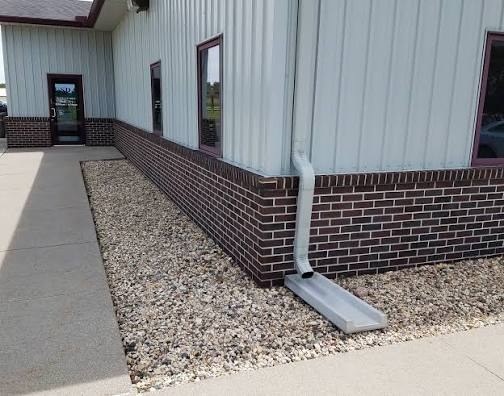 Gray downspout splash block directing water away from building foundation on gravel base in Kent, OH