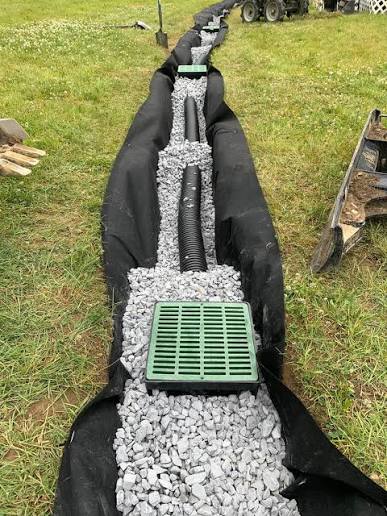 French drain installation with white gravel and black landscape fabric