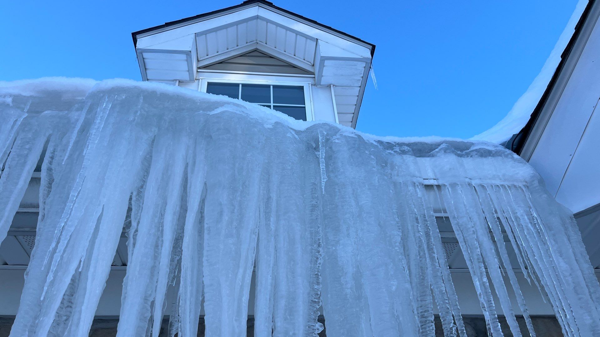 Heavy snow and ice buildup on residential roof before removal