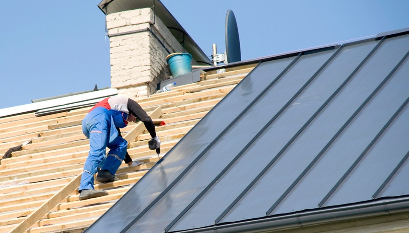 Professional contractor installing standing seam metal roofing panels on a residential property in Elyria, OH