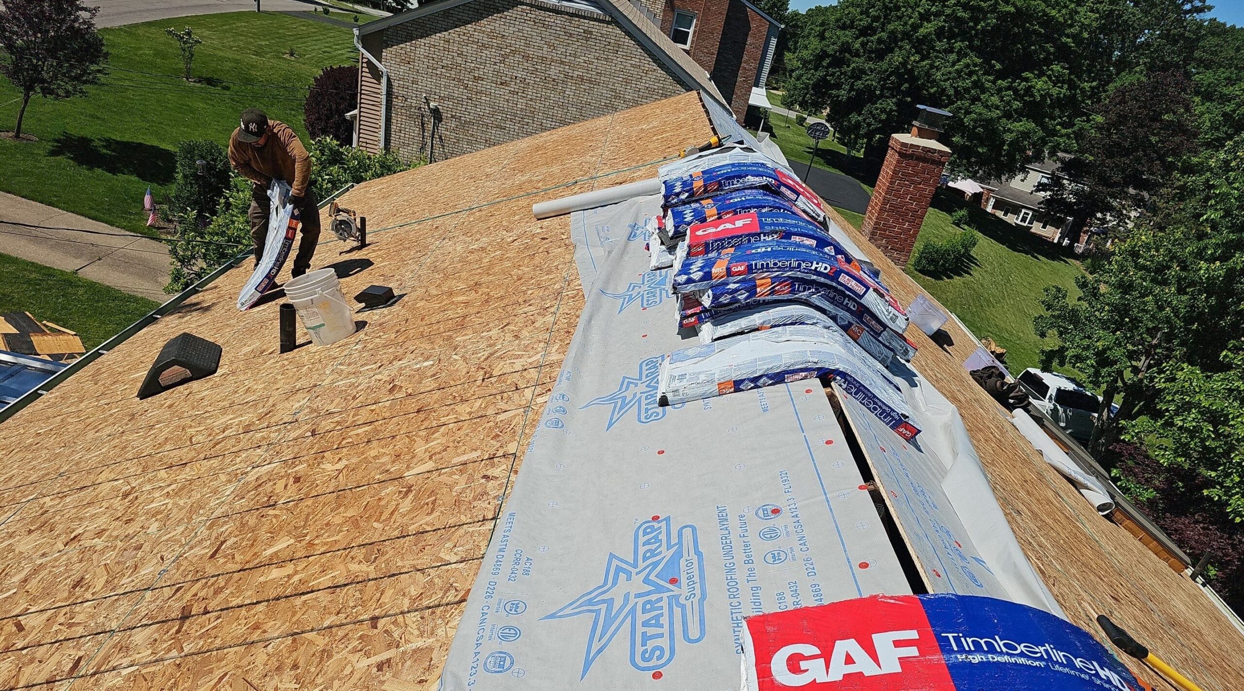 Workers installing GAF Timberline shingles and underlayment during residential roof replacement project in Cleveland, OH