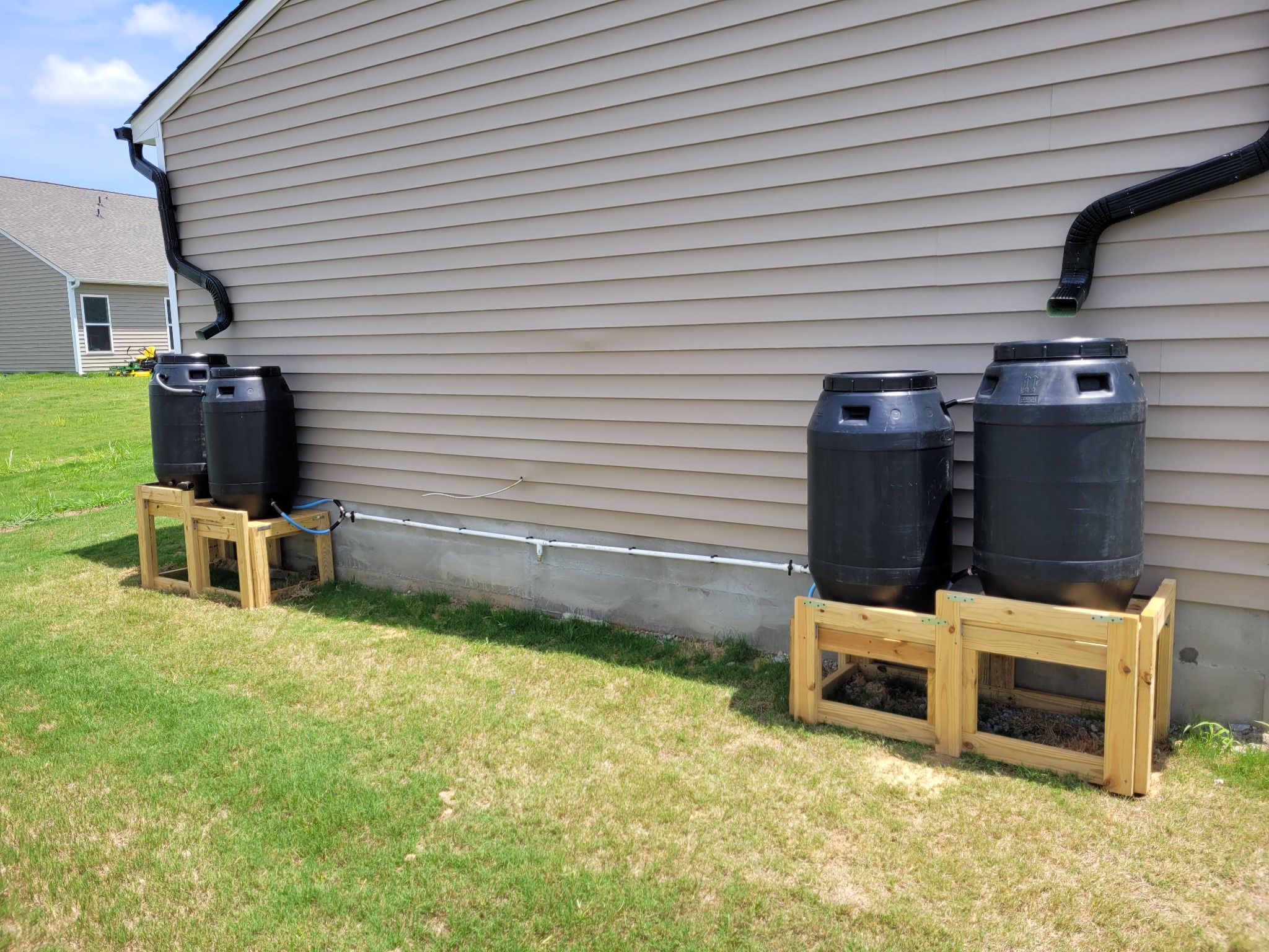 Rain Barrel Installation | Roof Gutter Now 2 Rain barrels on stands collecting gutter water