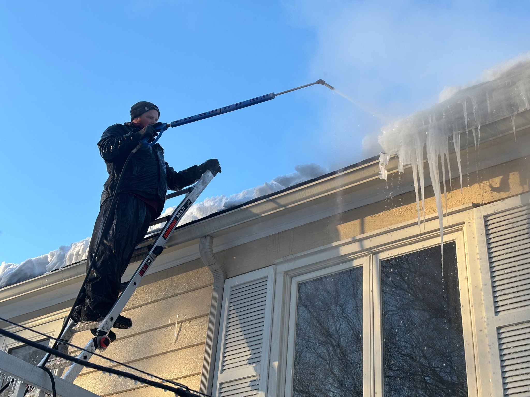 Ice Dam Removal Park City UT | Roof Gutter Now 10 Professional removing accumulated ice and snow from a home's roof during winter in Park City, UT