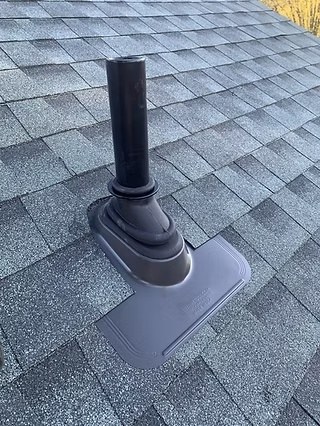 Black roof pipe boot flashing installed on asphalt shingles
