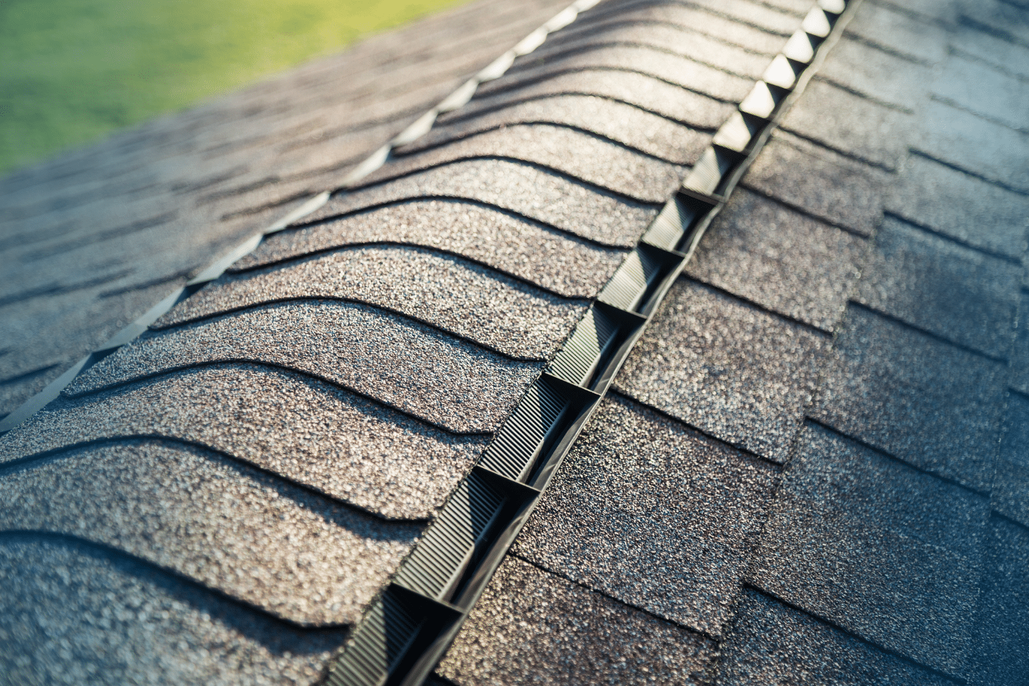 Asphalt shingles along roof ridge with metal vent system installed